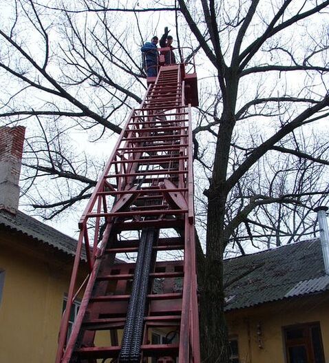 A large red ladder extended over a house that has been damaged in a storm